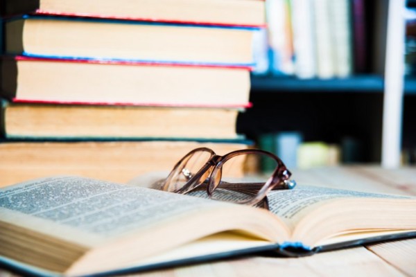 livro e óculos na mesa na biblioteca